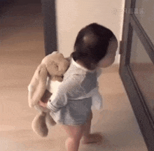 a baby is holding a stuffed animal on his back and walking .