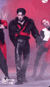 a man wearing a fur coat and leather pants is dancing on stage