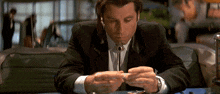 a man in a suit is sitting at a table with a cigarette in his mouth