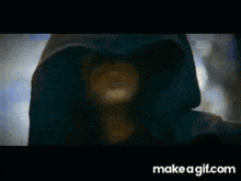 a grim reaper with a scythe is standing in the woods .