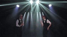 two men are dancing in front of a disco ball in a dark room