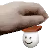 a hand is holding a marshmallow with a smile on it .