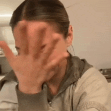 a woman is covering her face with her hand while sitting at a table .