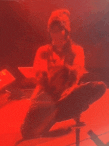 a person wearing a beanie is kneeling down in a red light