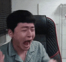 a man is sitting in a chair with his mouth open and making a funny face .