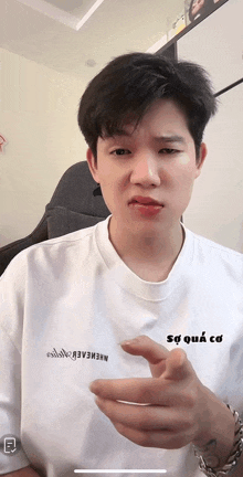 a man wearing a white t-shirt that says " sự quá cơ "