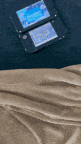 a nintendo 3ds is laying on a blanket on a bed