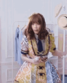 a woman in a dress and tie is standing in front of a clothes rack