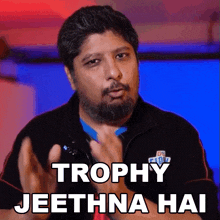 a man with a beard is wearing a jacket that says trophy jeethna hai