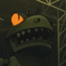 a close up of a cartoon character with a glowing orange eye and teeth .