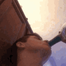 a man is drinking from a bottle with his eyes closed and his mouth open .