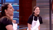 a group of women are standing next to each other in a kitchen and smiling .