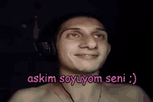 a shirtless man wearing headphones says " askim soyuyom seni " in pink letters