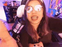a woman wearing glasses and headphones holds a game controller