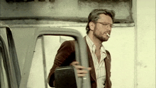 a man with a beard is smoking a cigarette while getting out of a truck .