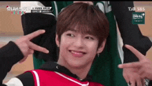 a young boy is making a peace sign with his fingers while smiling .
