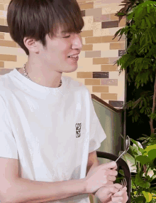 a young man wearing a loewe t-shirt holds a fork and spoon