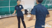 a man and a woman in police uniforms are dancing on a basketball court .