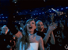 a woman in a white dress is holding a glass in her hand in front of a crowd at a concert .