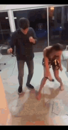 a man and a woman are dancing in a living room while holding a video game controller .