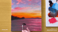 a person is painting a sunset on a canvas