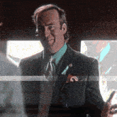 a man in a suit and tie is smiling and holding a phone