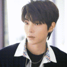 a close up of a young man wearing a black shirt and a plaid collar .