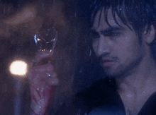 a man is holding a glass with blood on it