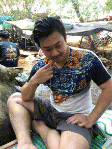 a man wearing a shirt with a dragon on it sits on a blanket