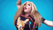 a woman with long blonde hair is wearing a black shirt with a lion on it and is dancing .