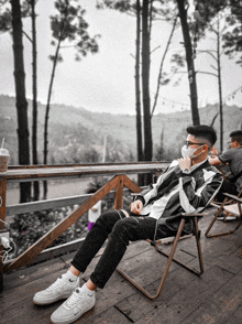 a man wearing a face mask sits on a deck