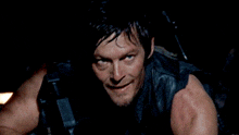 a man in a leather vest holds a gun