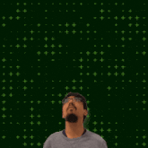 a man with glasses looks up at a green cross