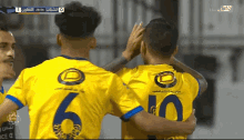 soccer players wearing yellow jerseys with the number 6 and 10 hugging each other