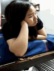 a woman laying on a bed with her head resting on her arm