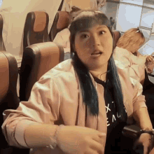 a woman in a pink jacket is sitting in a bus