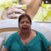 a woman in a green shirt is sitting in front of a picture of a woman 's face .