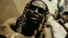 a close up of a man wearing sunglasses and a braided necklace .