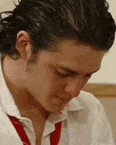 a man wearing a white shirt and a red tie looks down