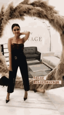 a woman in a black jumpsuit is standing in front of a dior display