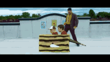 a man is standing next to two children in a box on a rooftop