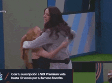 two women hugging in front of a sign that says vix premium vota hasta 10 veces por tu famoso favorito on it