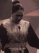 a woman in a black and gold dress with a bun