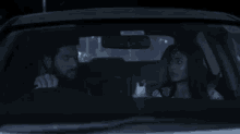 a man and a woman are sitting in a car at night
