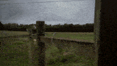 a wooden fence surrounds a grassy field with trees in the background on a cloudy day