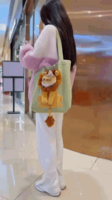 a woman is holding a tote bag with a stuffed lion on it