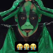a man with green and black face paint has three crying emojis below him