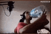 a man wearing headphones is drinking water from a bottle .
