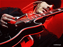 a man is playing a guitar with a red background and the words airbaggifs on the bottom