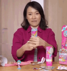 a woman in a pink jacket is sitting at a table holding a candy cane .